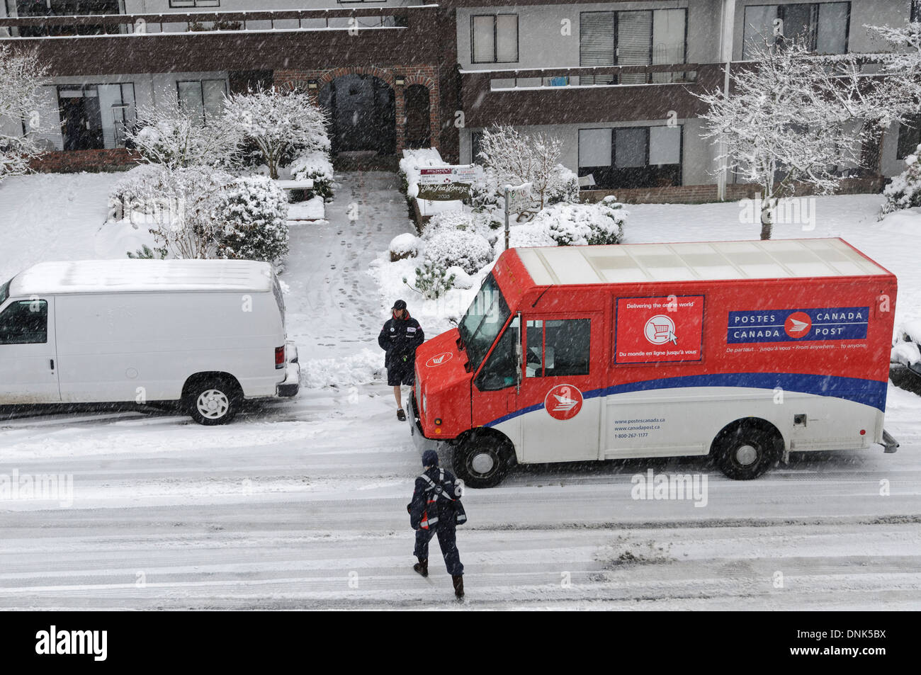 Mail delivery on a snowy Vancouver day. A letter carrier talks briefly