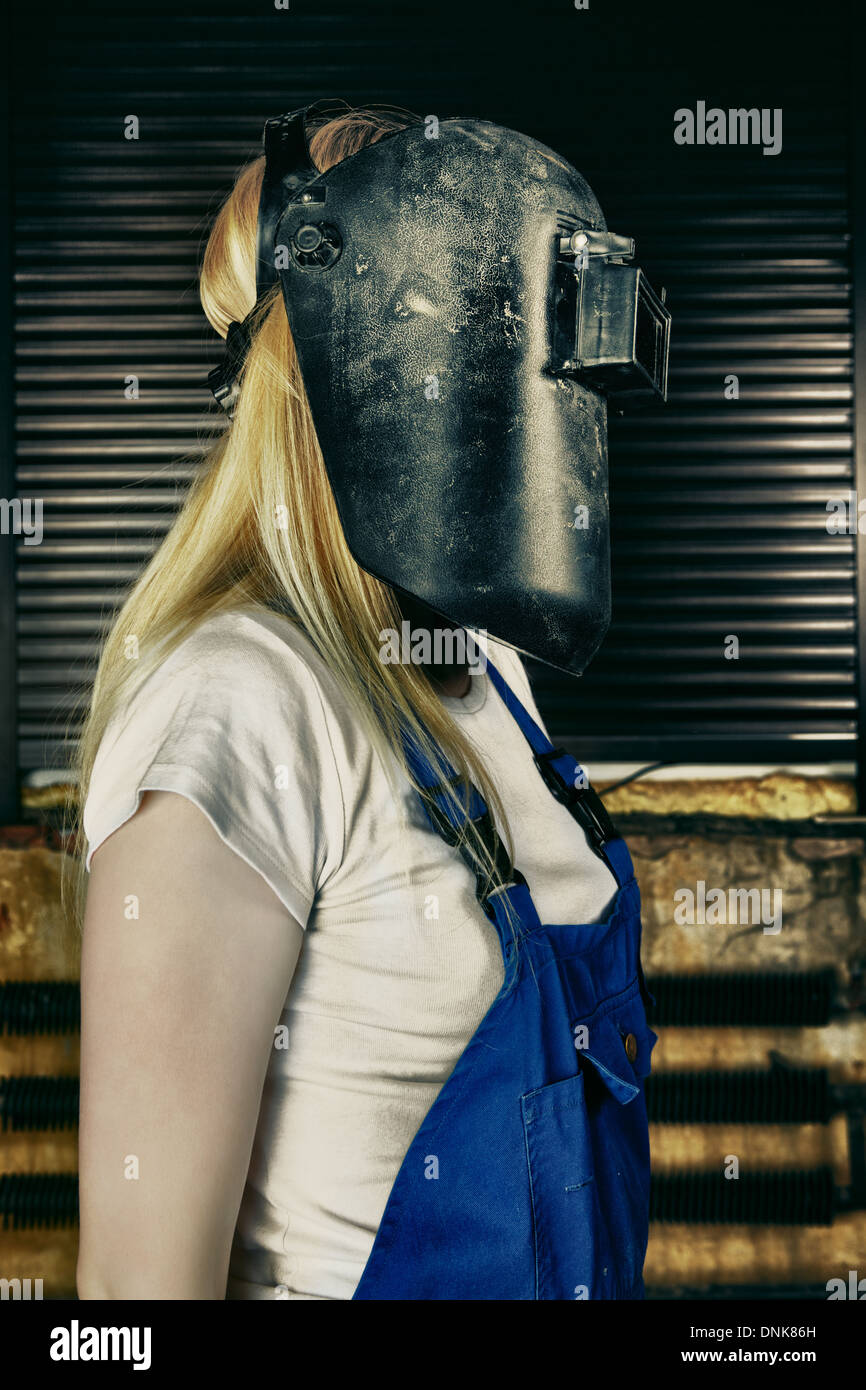 blond woman in overall and welder helmet Stock Photo Alamy