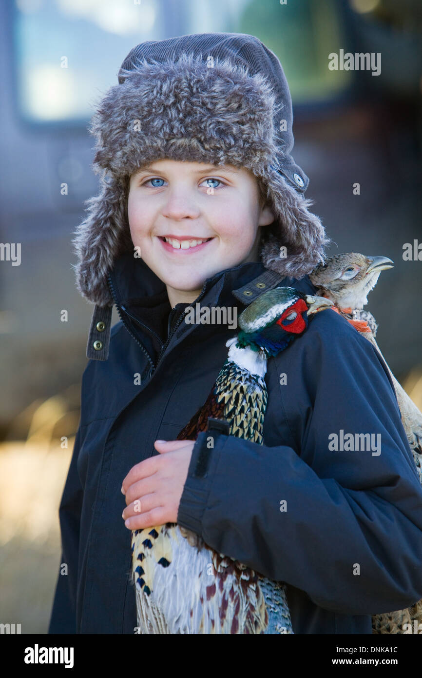 A young boy carrying a brace of dead pheasants on a pheasant shoot in England Stock Photo