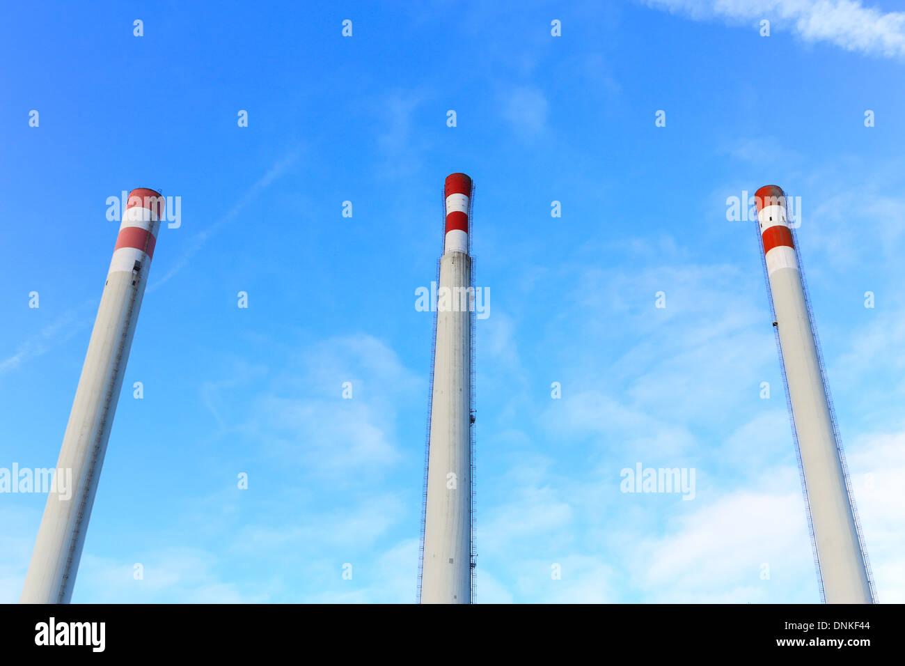 Three tall white and red chimney, no smoke, on blue cloudy sky. landscape, nobody Stock Photo