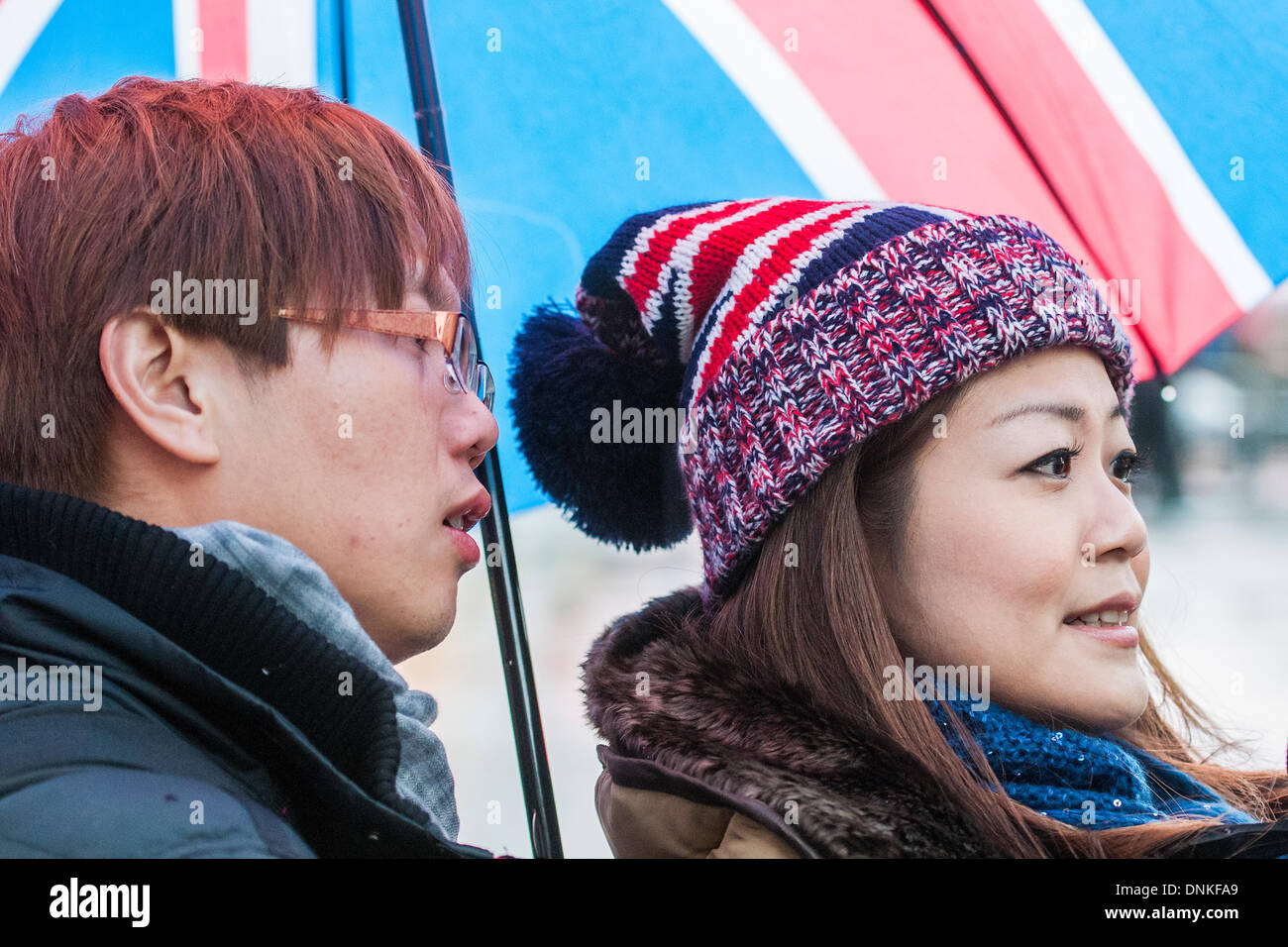 London, UK. 01st Jan, 2014. A new year's day parade passes through Piccadilly Circus on a wet and windy day.Many of the spectators are foreign and have just stocked up on Union Jack branded items.  London, UK 01 Jan 2014. Credit:  Guy Bell/Alamy Live News Stock Photo