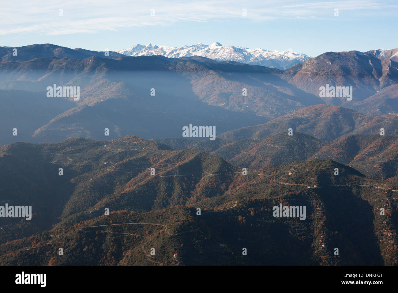 AERIAL VIEW. Nervia Valley with the southern snowcapped alps in the distance. Italian Riviera's backcountry. Province of Imperia, Liguria, Italy. Stock Photo