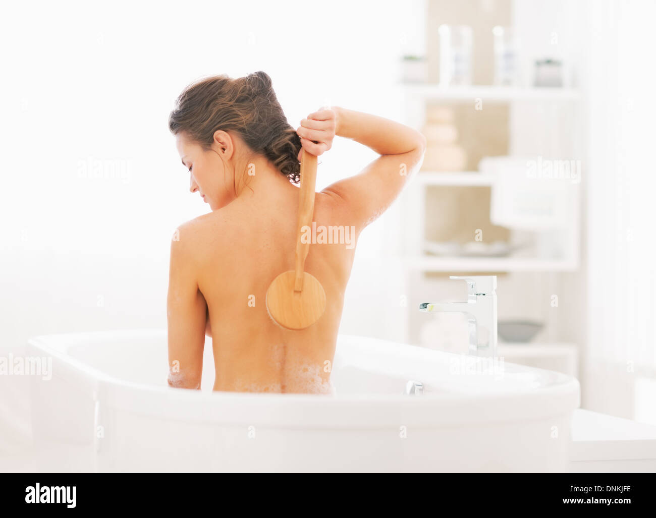 Young woman washing with body brush in bathtub Stock Photo