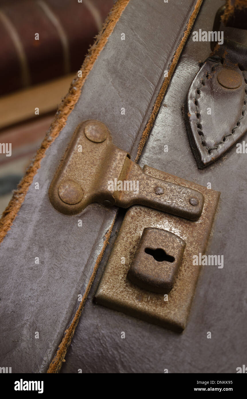Old fashioned leather suitcase lock and latch undone in room with warm
