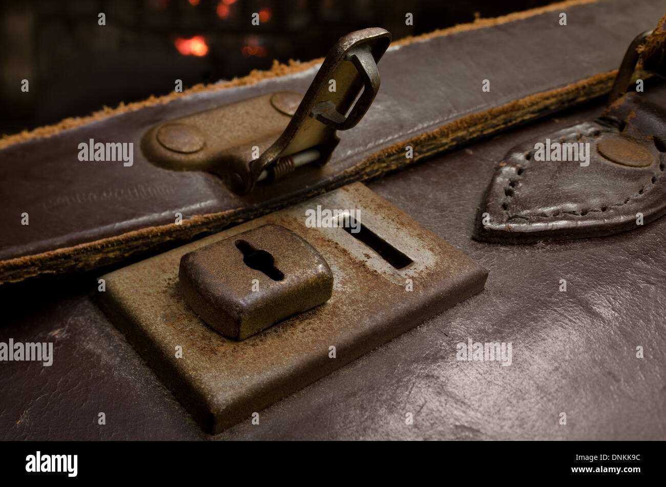 Old fashioned leather suitcase lock and latch undone in room with warm