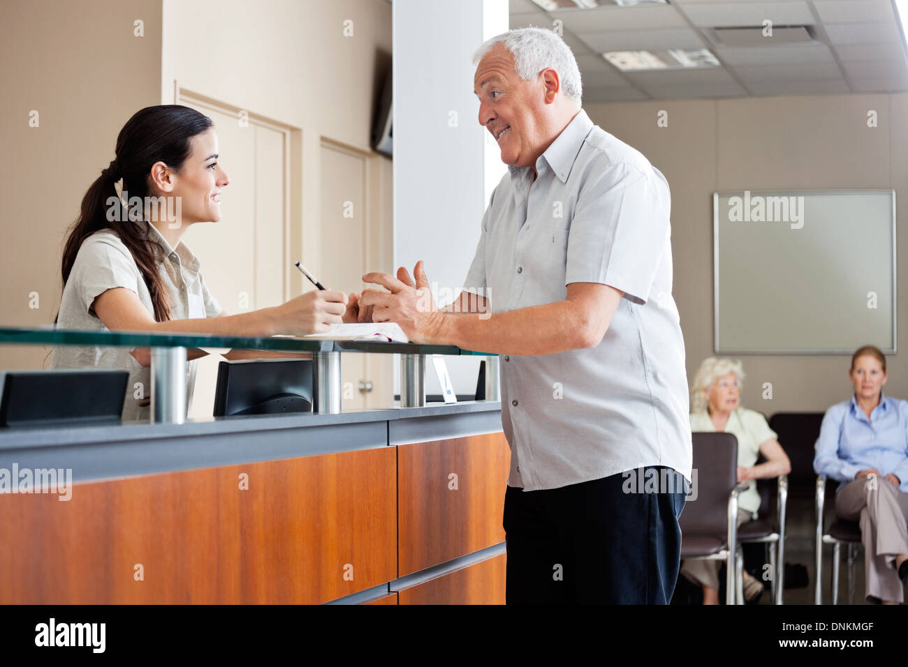 Man Communicating With Female Receptionist Stock Photo