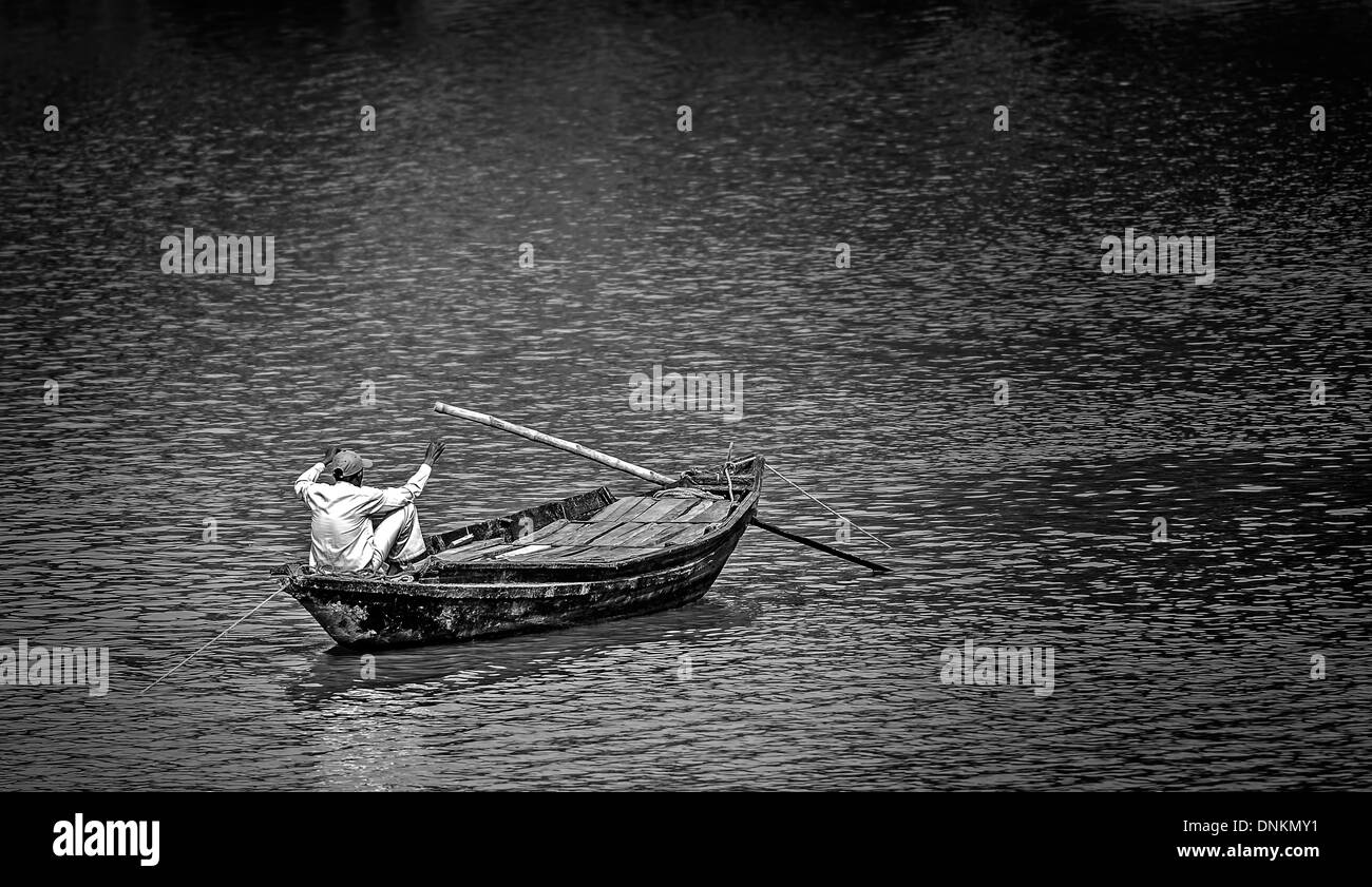 A Fisherman of West Bengal fishing from River Damodar from his country boat in black and white and copy space Stock Photo