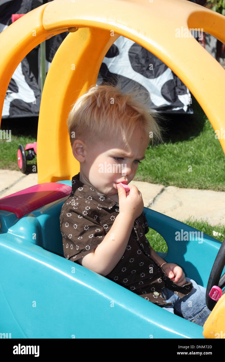 A young boy sitting and playing in his playcar Stock Photo