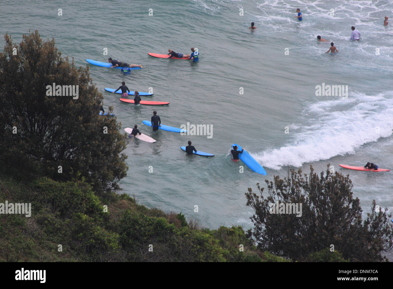 A photograph of a groups of surfers learning to surf at the beach in Australia. Stock Photo