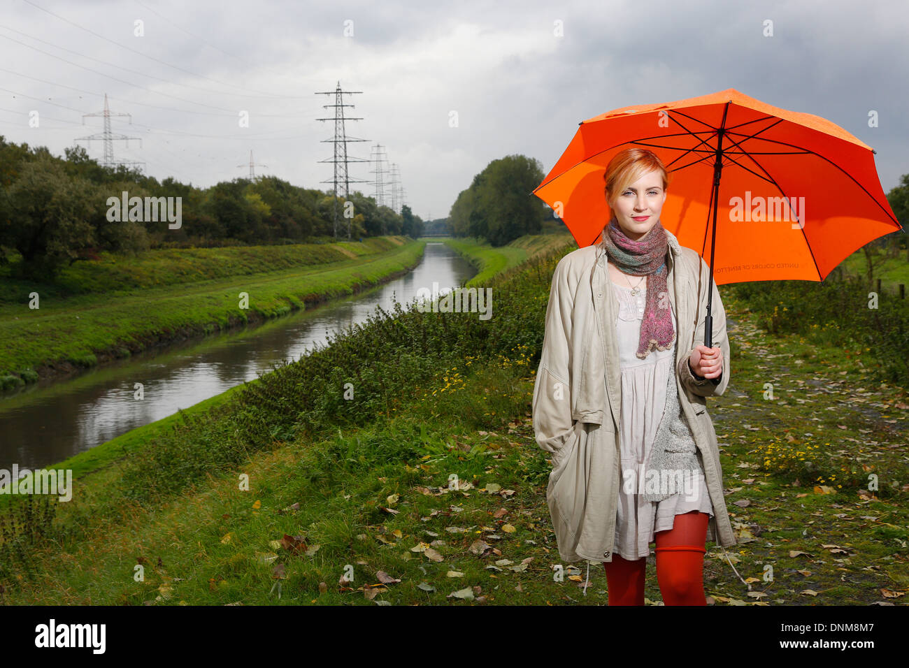 Oberhausen, Germany, a young woman walks in the rain with umbrella walking along the Emscher Stock Photo