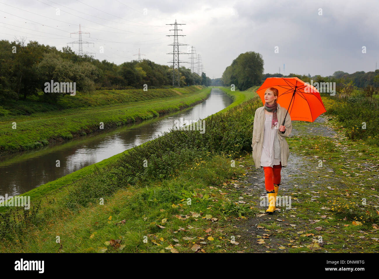 Oberhausen, Germany, a young woman walks in the rain with umbrella walking along the Emscher Stock Photo