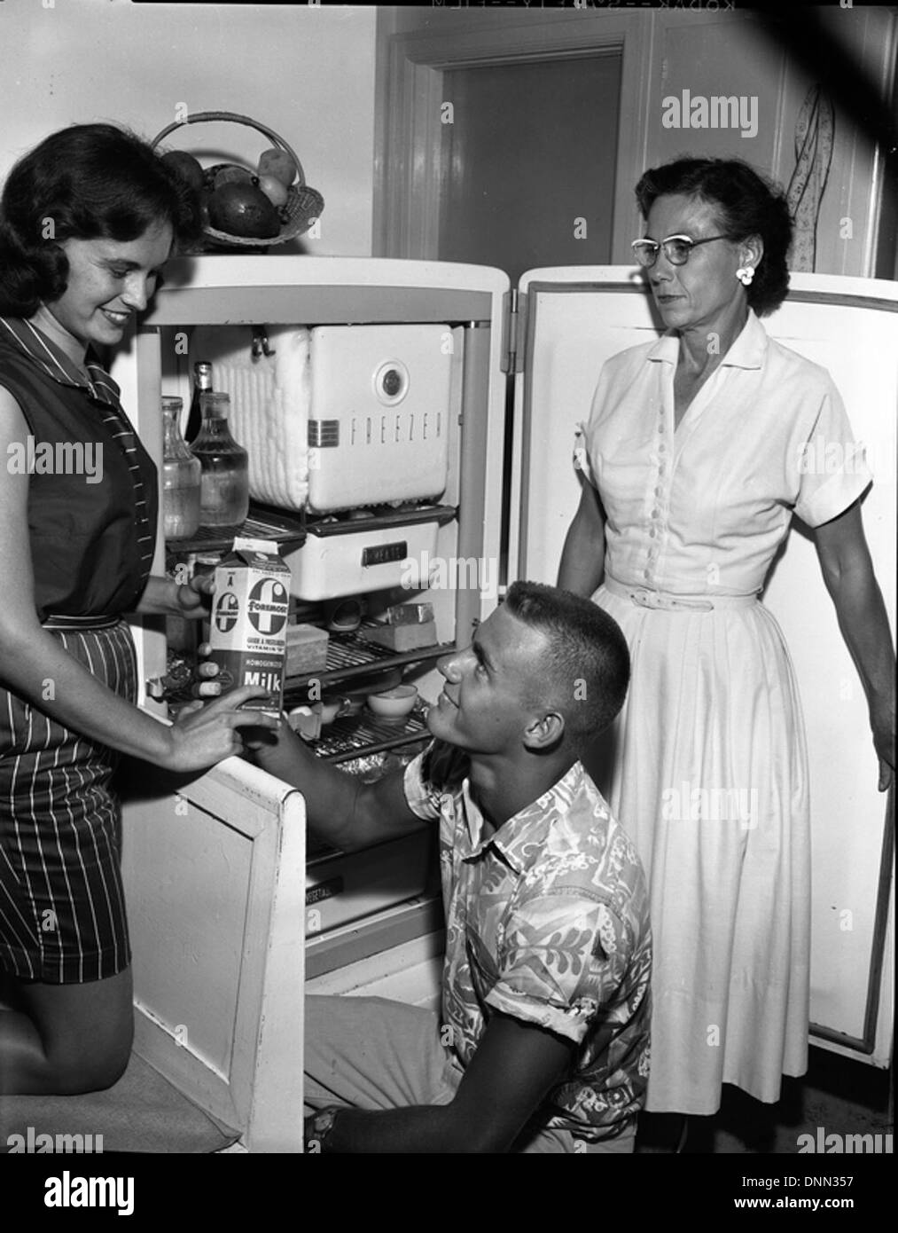 Teenagers are captured raiding the refrigerator in a Tallahassee home during the 1950s. The image humorously reflects everyday family life in Florida during that time period. Stock Photo