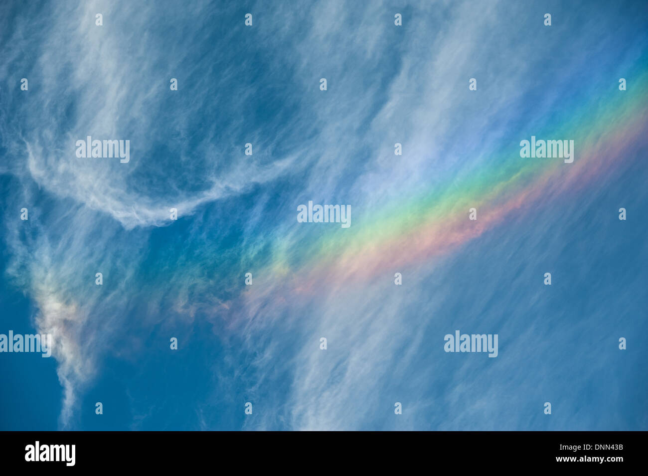 The beautiful brush of color through white, wispy clouds of a 'fire rainbow' or rainbow cloud. Stock Photo