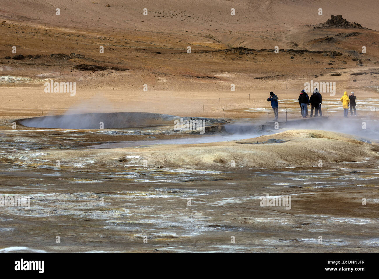 Tourists on the Hverarond geothermal hot spring area examining the steaming and bubbling mud pools, north east Iceland Stock Photo