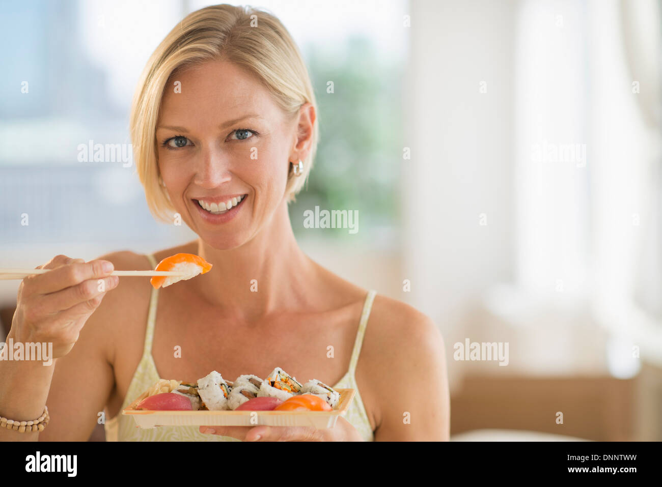 Portrait of woman eating sushi Stock Photo
