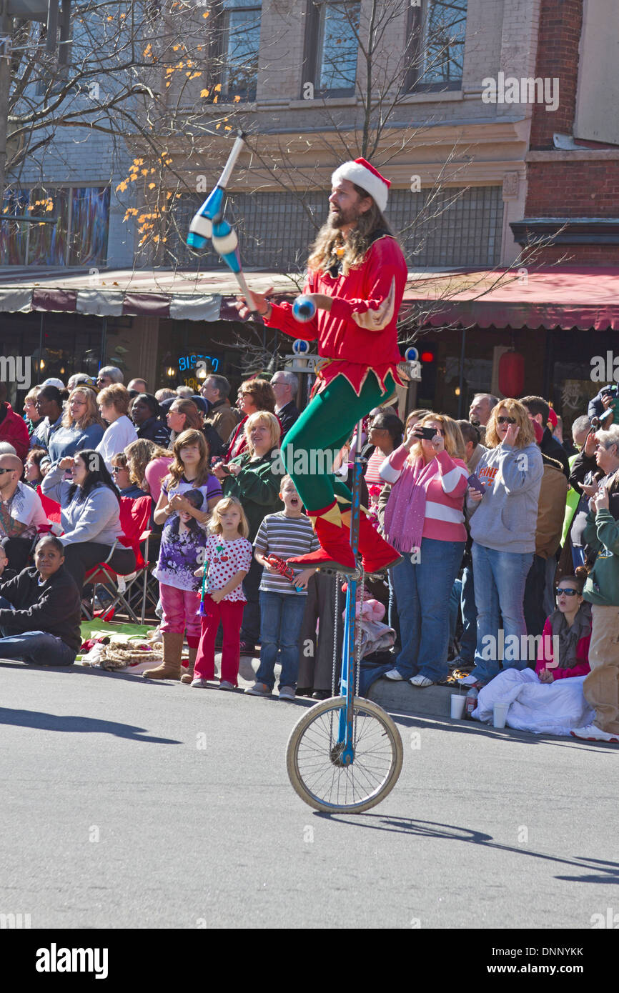 Asheville, North Carolina, USA - November 17, 2012: A colorful juggler dressed like an elf rides a unicycle entertains kids and Stock Photo