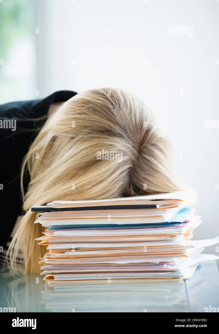 Businesswoman sleeping on stack of files Stock Photo
