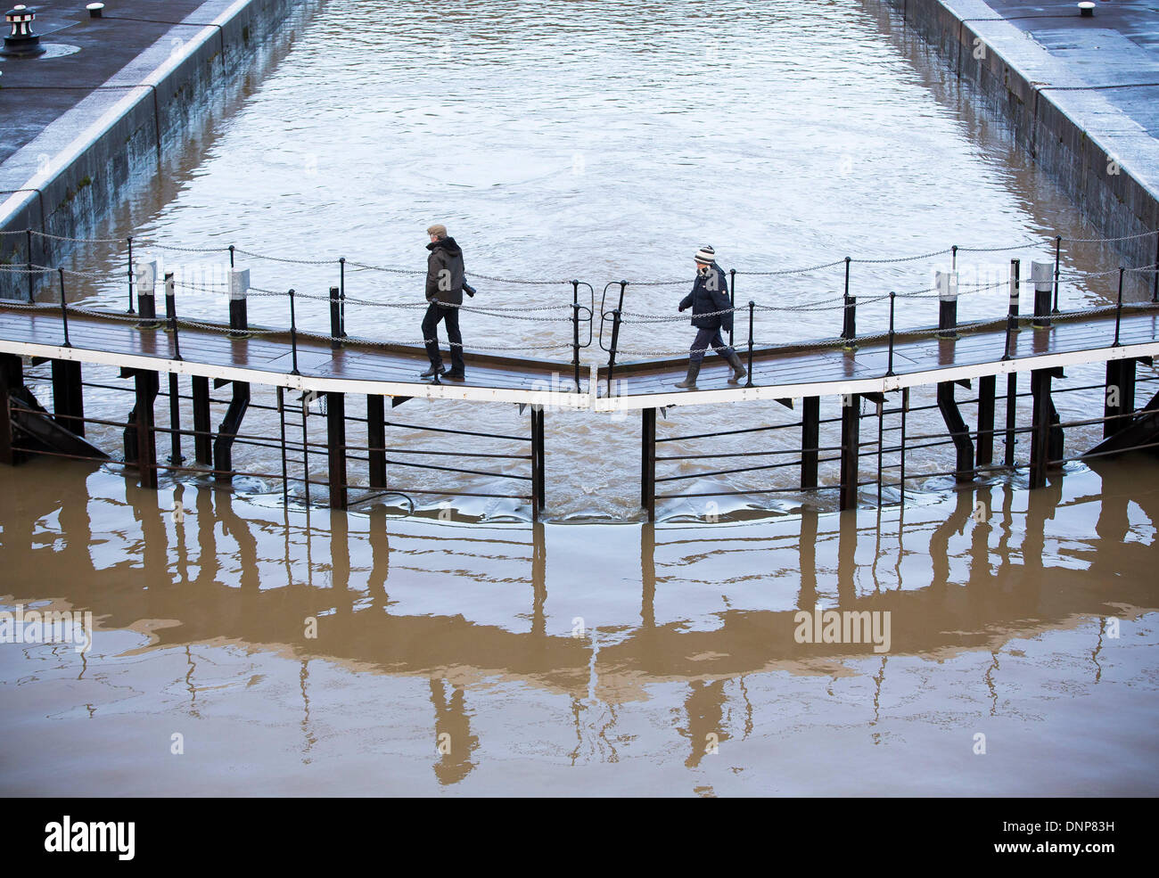 Bristol, UK. 3rd January 2014. People walk over a breached lock on the swollen river Avon in Bristol following high tides and heavy rain. 3 January 2014 Credit:  Adam Gasson/Alamy Live News Stock Photo