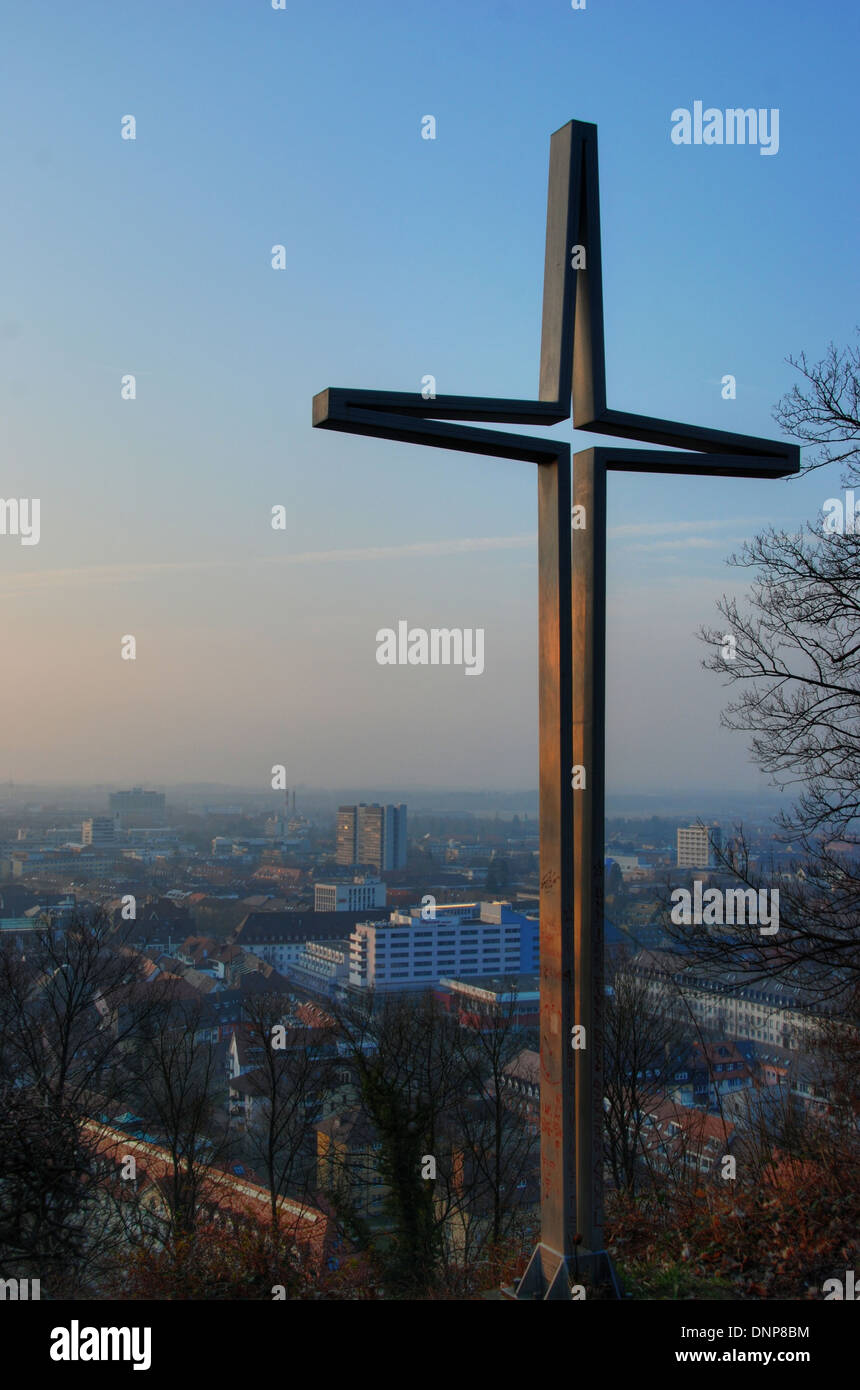 Cross at dusk, with a view over the town of Freiburg, Germany Stock Photo