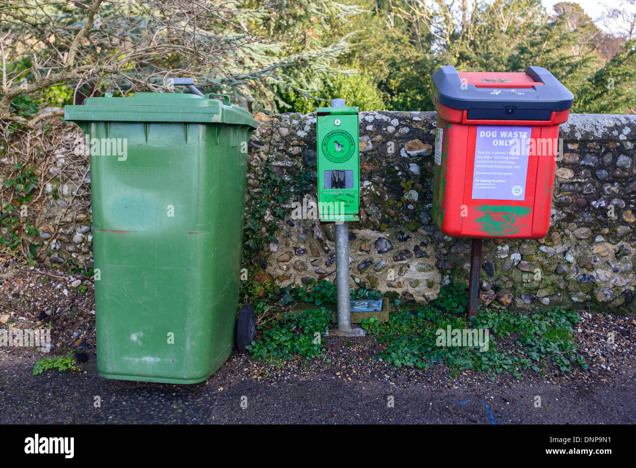 A red dog waste bin, poopascoop dispenser and green wheelie bin