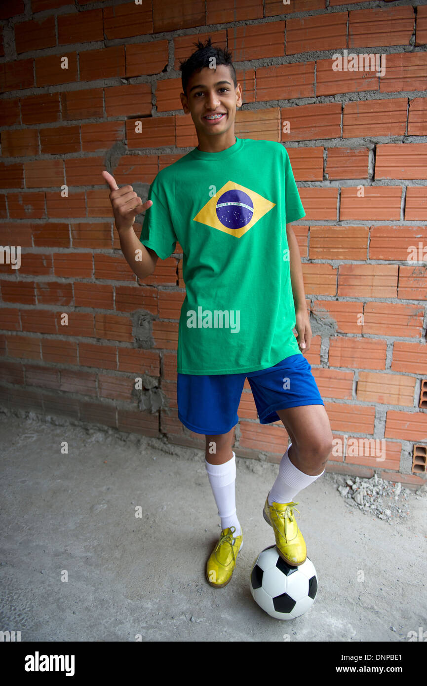 teen brazilian Smiling Brazilian teen wearing Brazilian flag t-shirt standing by rustic favela wall giving thumbs up with football soccer ball Stock Photo - Alamy