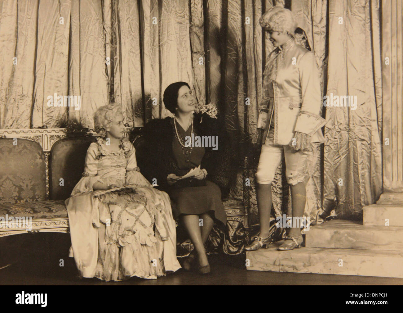 photograph of Princess Margaret (left) and Princess Elizabeth (right) with the Queen Mother on the set of the play Aladdin, 1943 Stock Photo