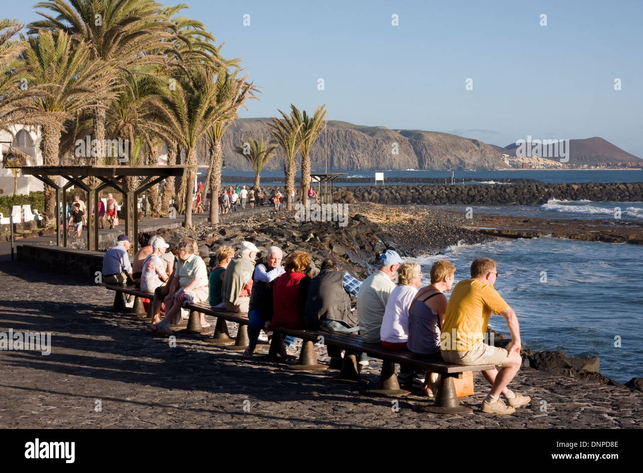 mature people sitting on bench looking out to sea, Playa del Camison, Tenerife, Spain Stock Photo