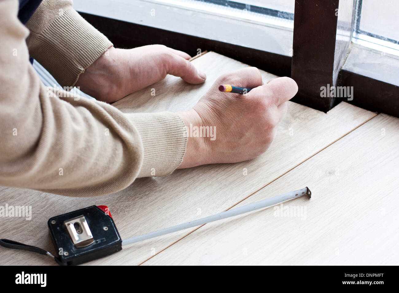 worker makes markup before laying laminate flooring Stock Photo