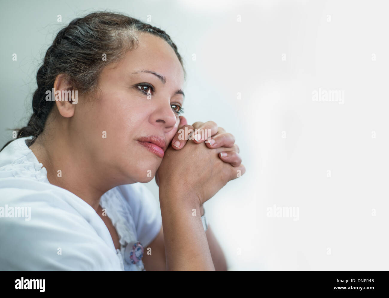 Contemplative Hispanic Woman against a light background Stock Photo