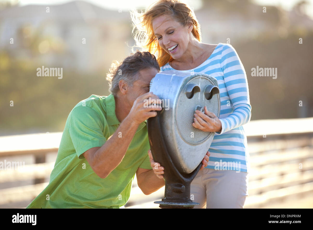 Mature Couple being Playful looking through Scenic Viewer on Pier, USA Stock Photo