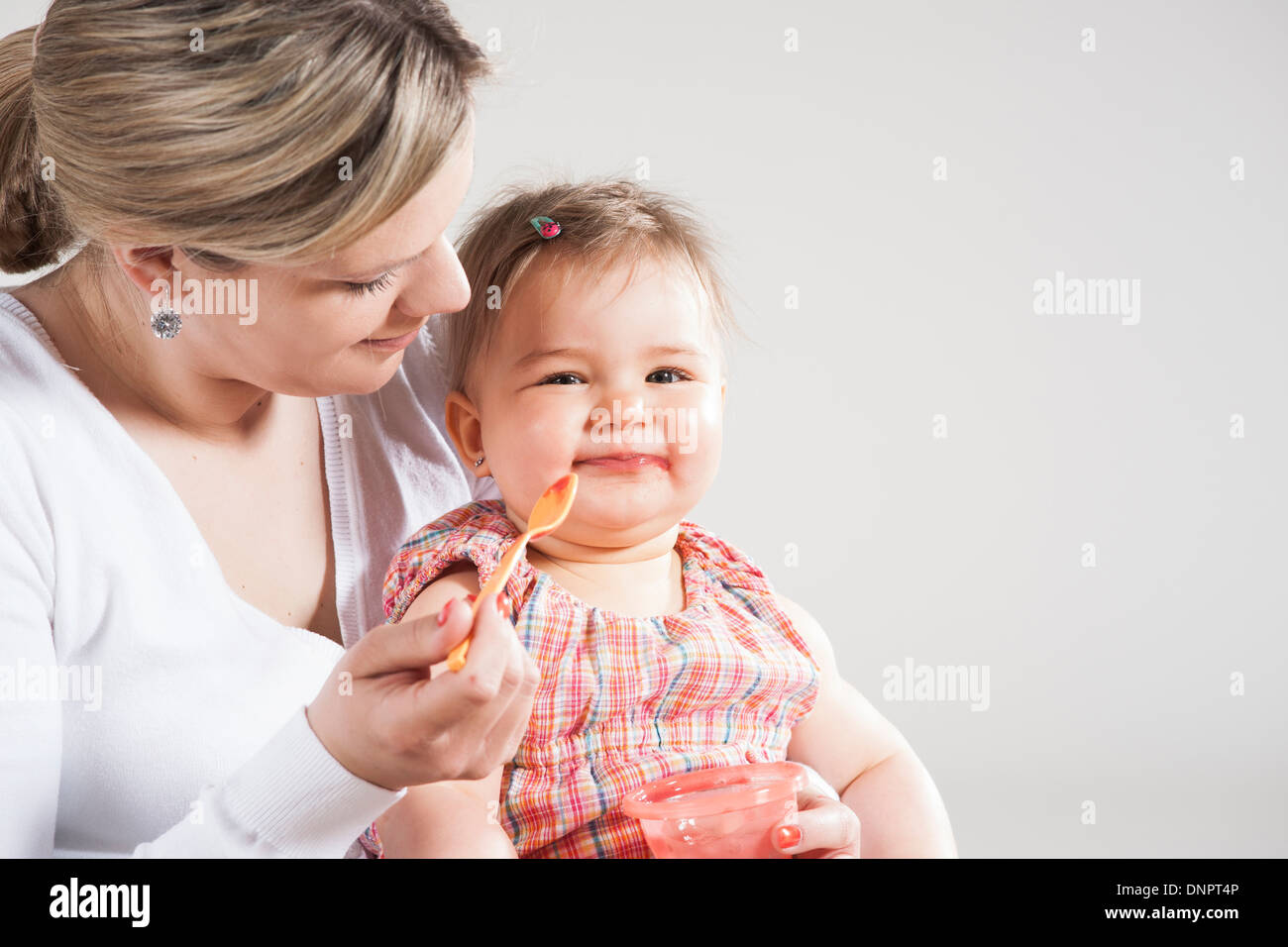 Portrait of Mother Feeding Daughter, Studio Shot Stock Photo