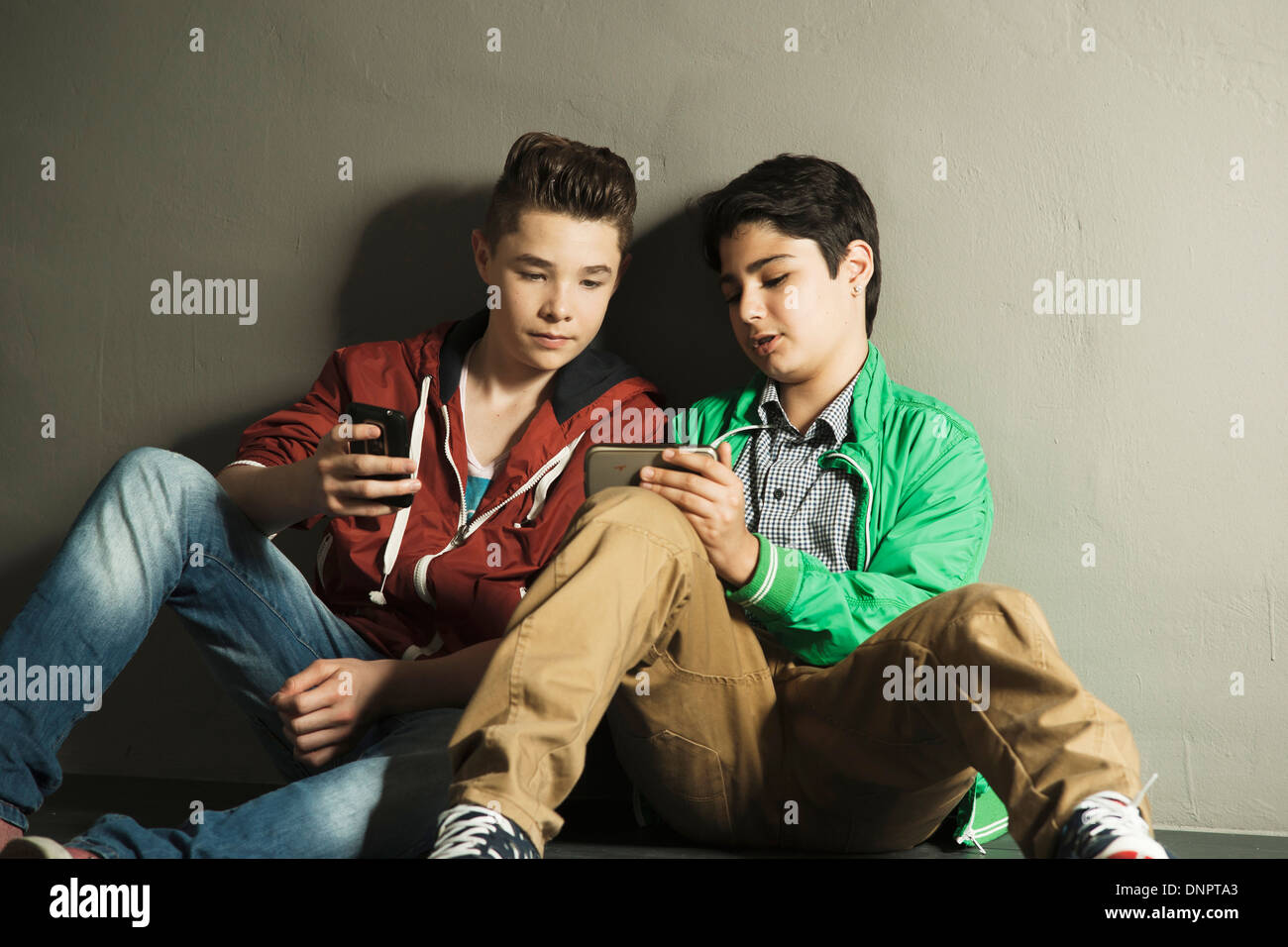 Teenagers looking at Cell Phones, Studio shot Stock Photo