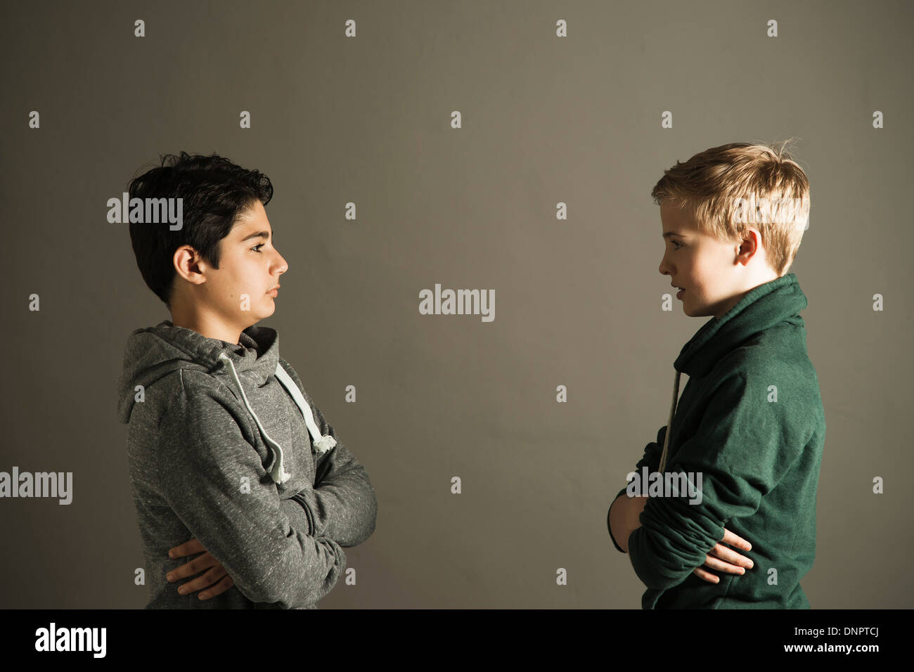 Teenage Boys with Arms Crossed looking at Each Other, Studio Shot Stock Photo