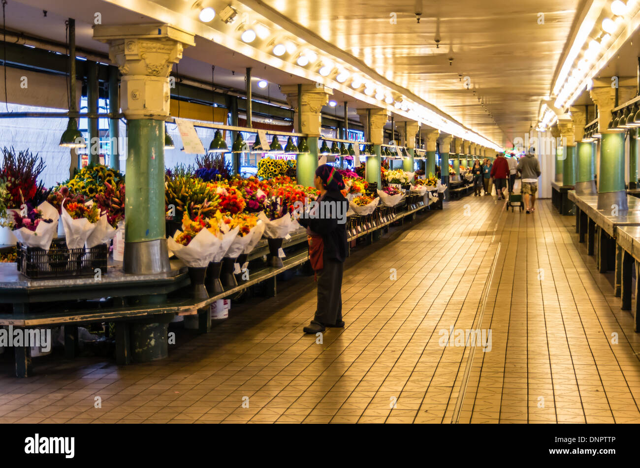 Flower vendor checks the display at a flower market stall Pike Place Market Seattle, Washington, USA Stock Photo