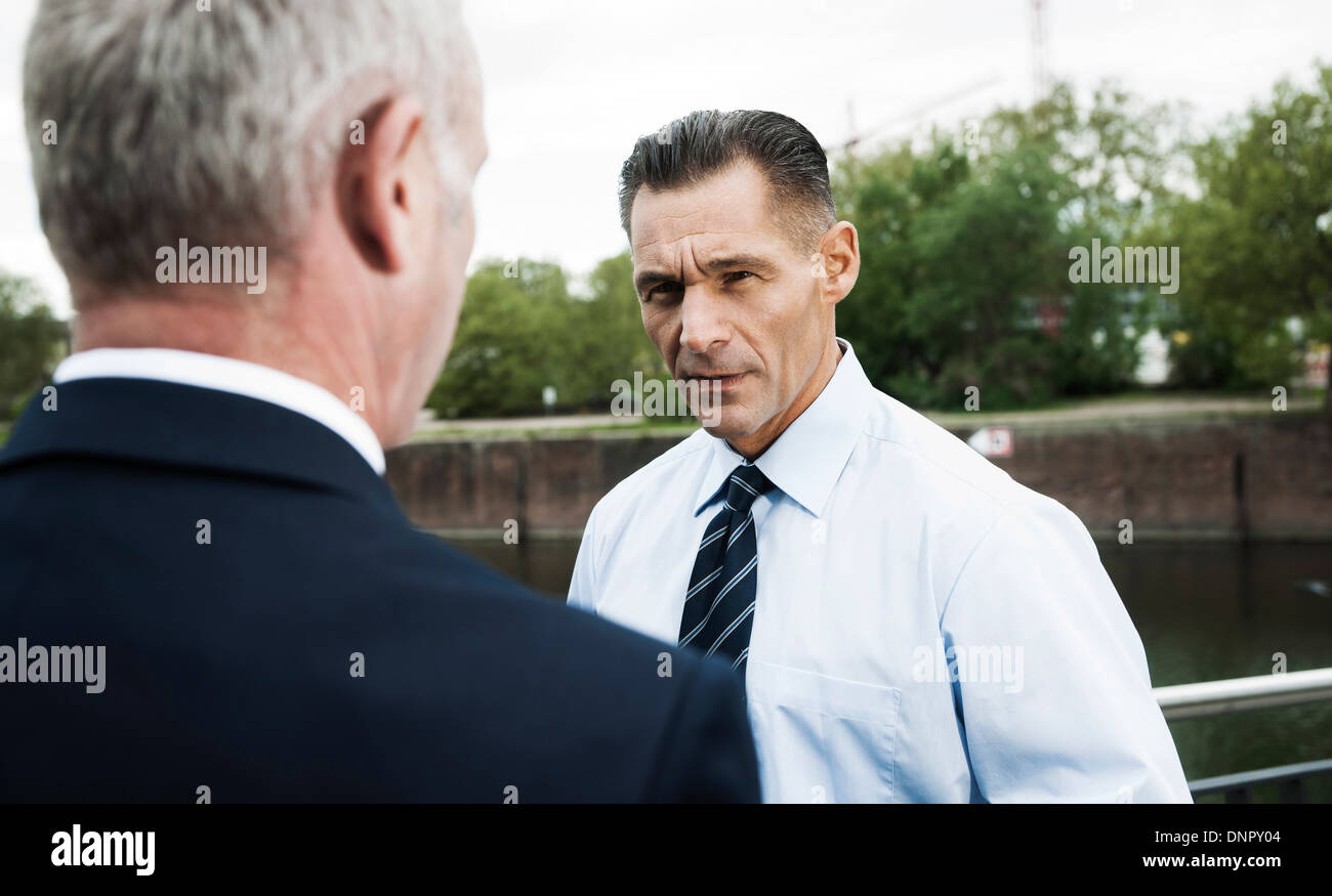 Mature businessmen standing by railing, talking, Mannheim, Germany Stock Photo