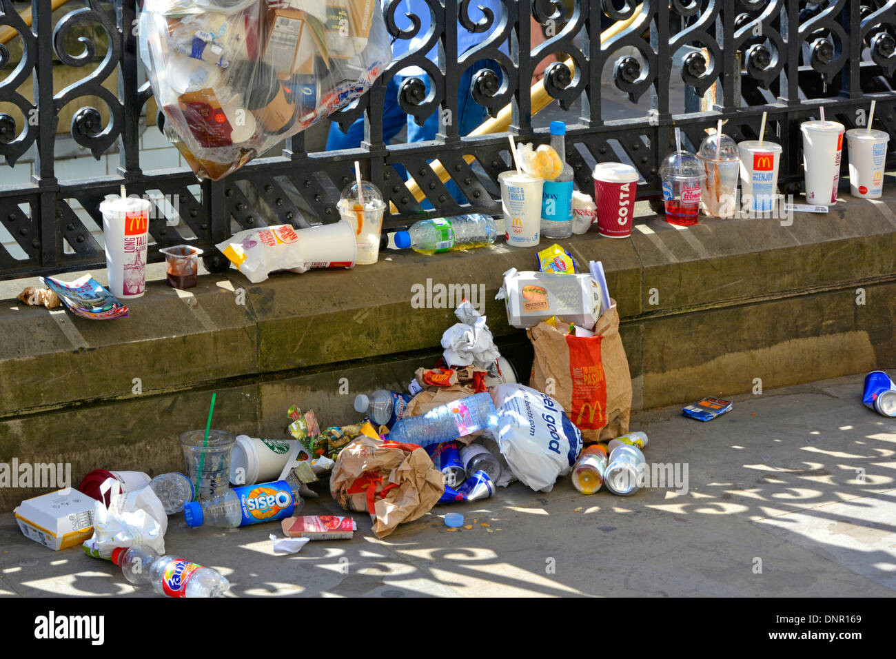 Disgusting fast food  packaging drinks & cups litter dumped on pavement in major tourist area beside Westminster subway sunny day in London England UK Stock Photo