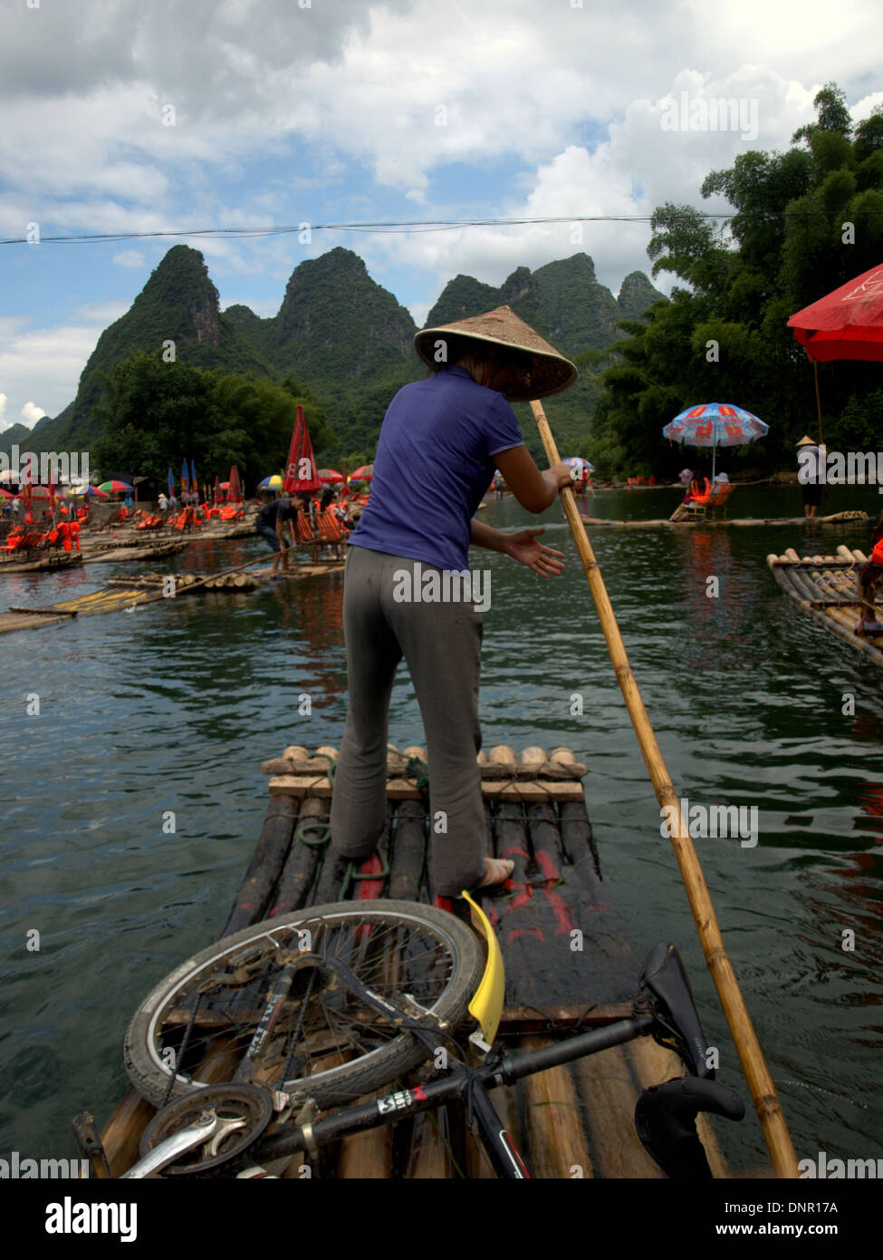 Woman guiding traditional bamboo raft on Li River near Yangshuo and ...