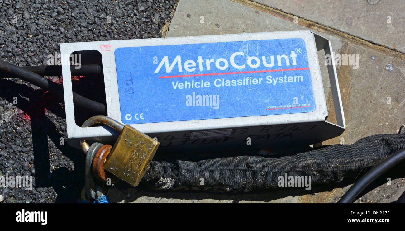 Metro Count vehicle classifier traffic data collection box at pavement end of activation tubing across tarmac road surface Stock Photo