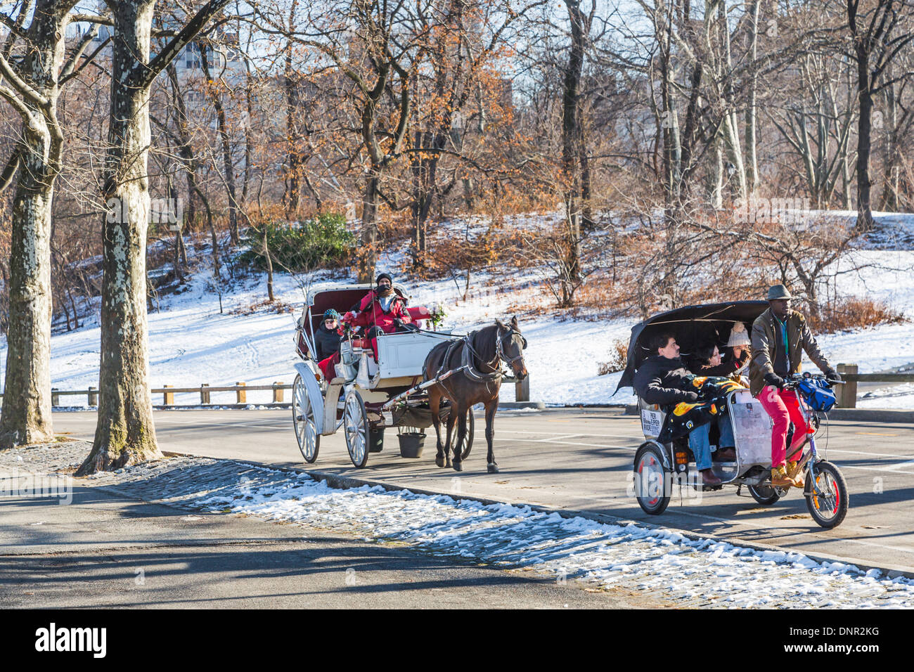 Tourists enjoy horse and carriage and cycle taxi rides in the snow in winter in Central Park, New York, USA Stock Photo