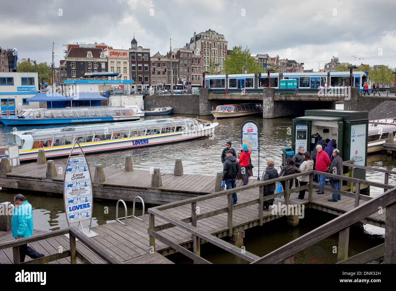 People waiting on a wooden pier for canal cruise in Amsterdam, Holland, Netherlands. Stock Photo