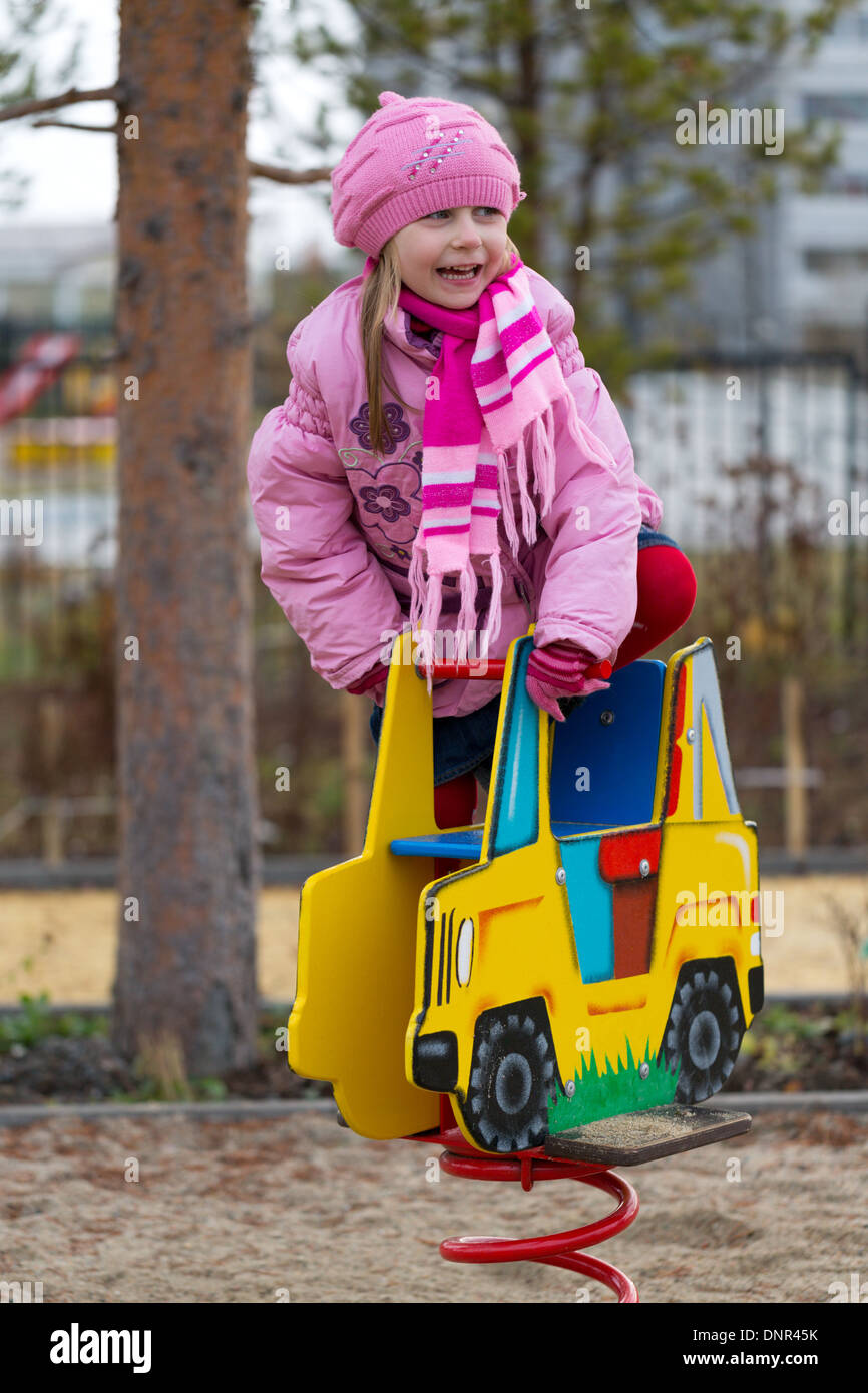 Little girl on the carousel in the autumn clothes. Stock Photo