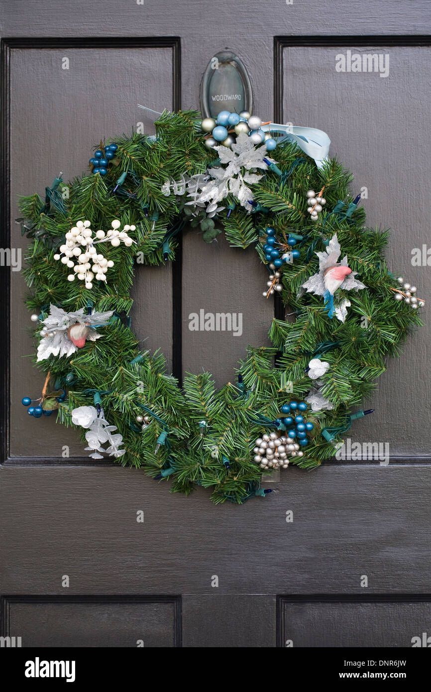 Decorative Christmas wreath hanging on a dark front door. Stock Photo