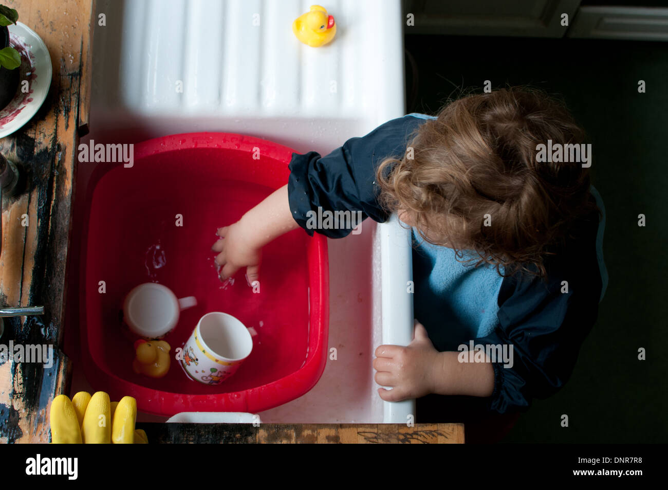 toddler playing in washing up bowl Stock Photo