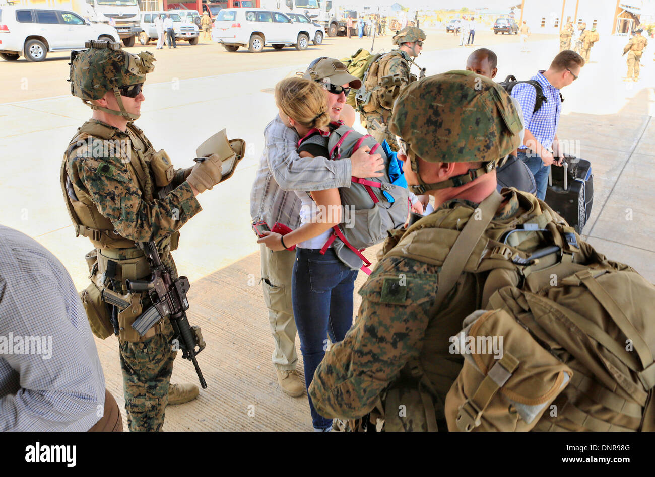 A US Marine from the Crisis Response team guides American citizens to an evacuation flight January 3, 2014 in Juba, South Sudan. The Marines evacuated more than 20 personnel from the U.S. Embassy as conflict escalates in South Sudan following a failed coup attempt. Stock Photo