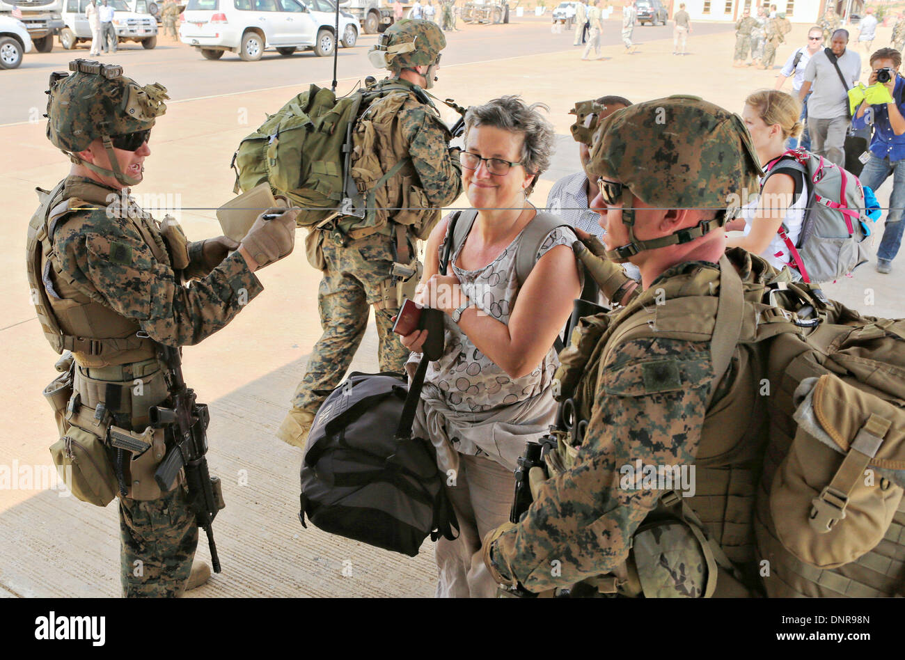 A US Marine from the Crisis Response team guides American citizens to an evacuation flight January 3, 2014 in Juba, South Sudan. The Marines evacuated more than 20 personnel from the U.S. Embassy as conflict escalates in South Sudan following a failed coup attempt. Stock Photo