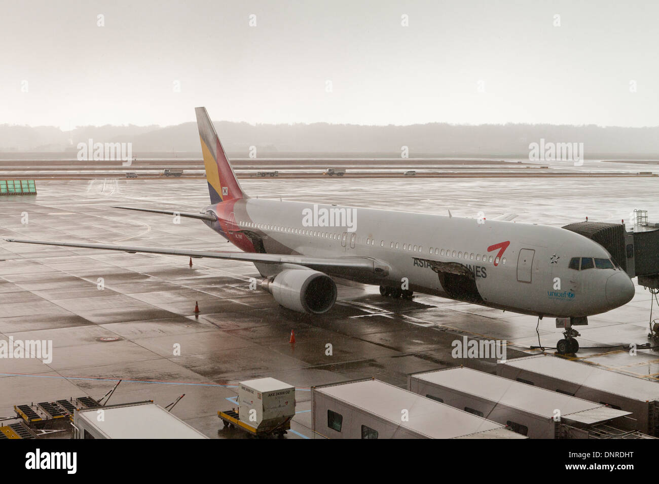 Asiana Boeing 707 plane docked in rainy weather at Incheon International Airport - South Korea Stock Photo
