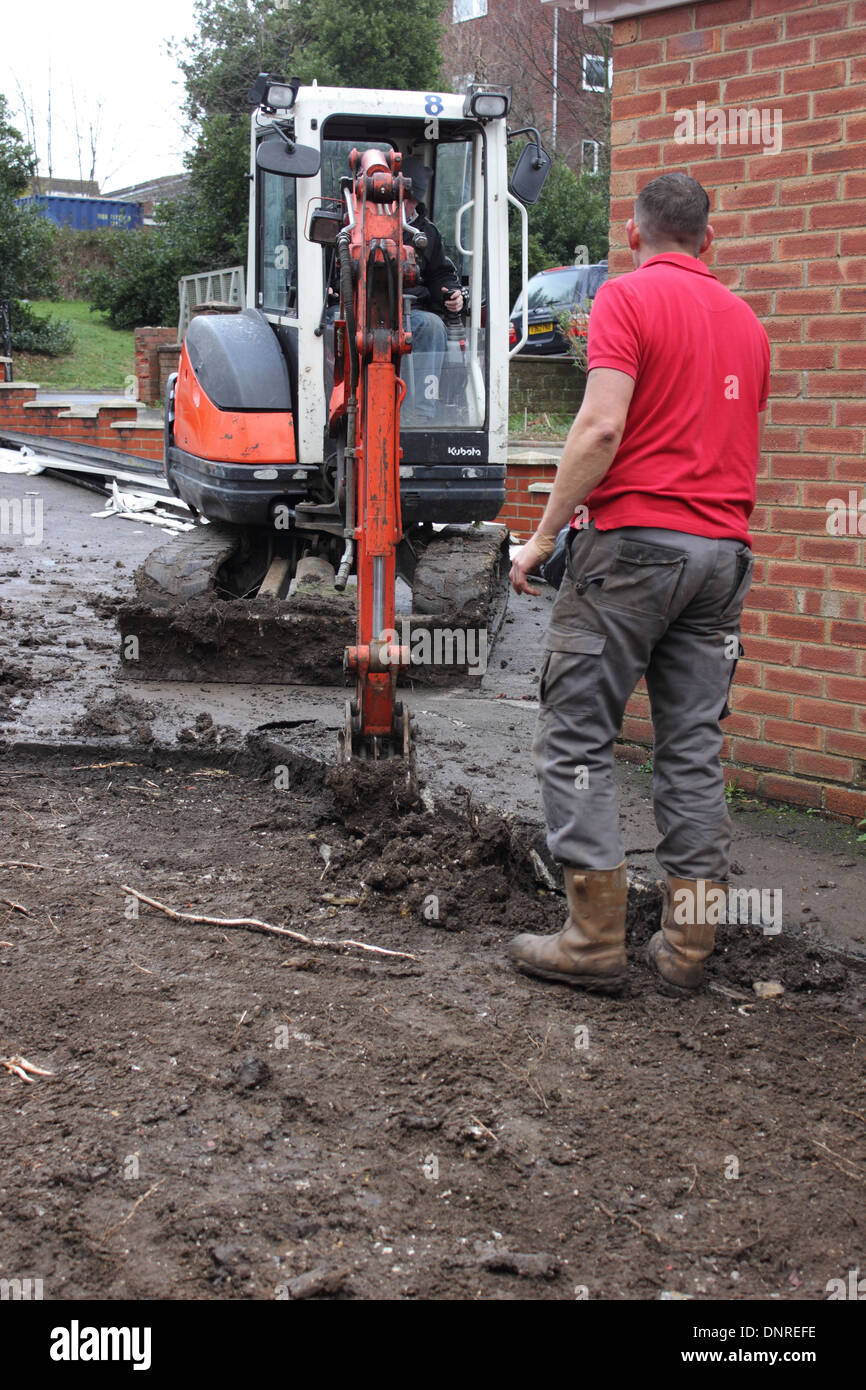 A mini digger being used in the preparation of groundwork for the laying of blockpaving Stock Photo