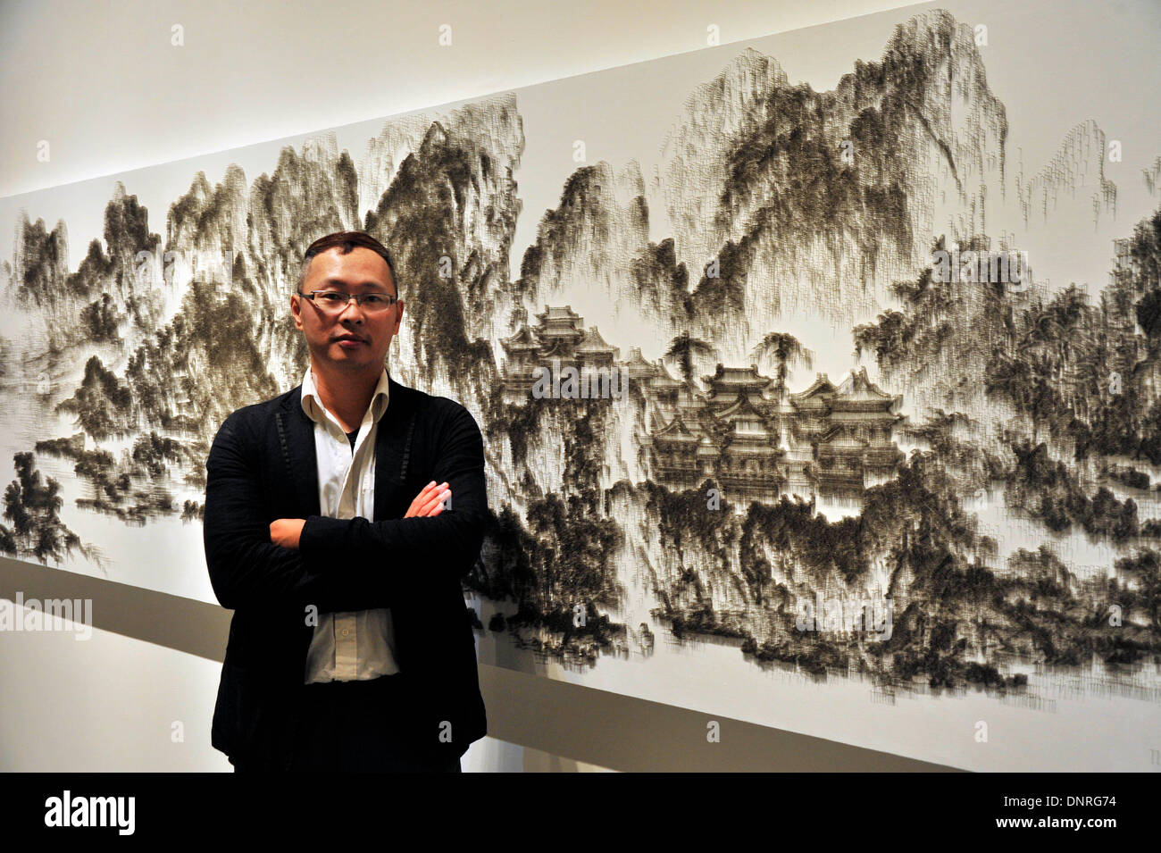Taipei, China's Taiwan. 4th Jan, 2014. Chen Chun-Hao poses with his works at his exhibition in Taipei, southeast China's Taiwan, Jan. 4, 2013. Chen is a Taiwanese artist who replaces paintbrush with nail guns in copying the traditional Chinese ink paintings. He uses a nail gun to shoot thousands of small mosquito nails, or headless nails, into a canvas-covered wood board to reproduce traditional Chinese ink masterpieces. © Wu Ching-teng/Xinhua/Alamy Live News Stock Photo
