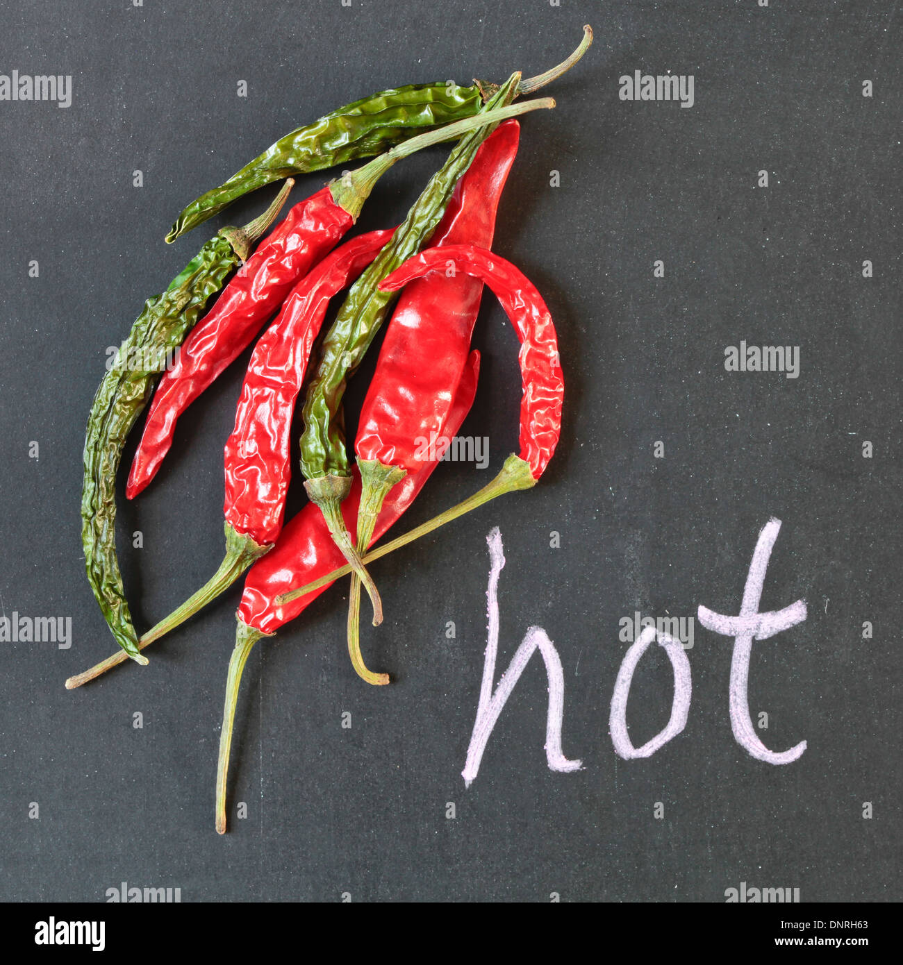 Green and red chilli peppers on a black surface Stock Photo