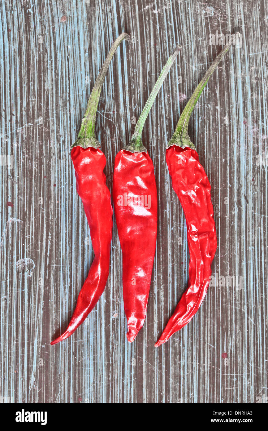 Three red chilis on a blue wooden background Stock Photo